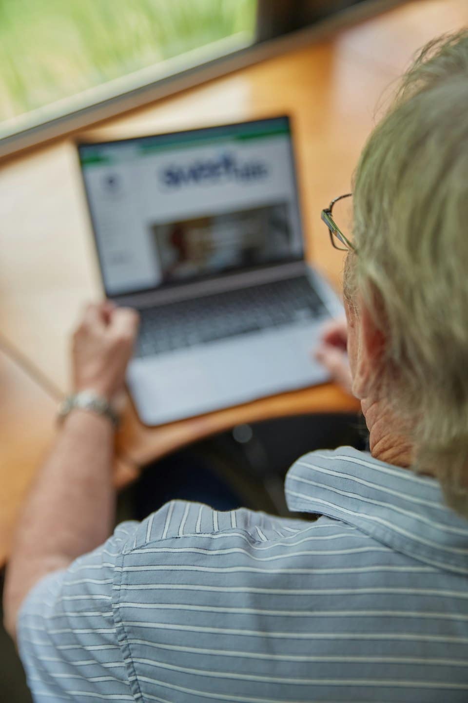 Person in a striped shirt types on a laptop computer.